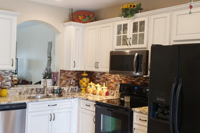 Example of a mid-sized minimalist l-shaped eat-in kitchen design in Tampa with raised-panel cabinets and white cabinets