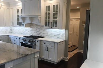 Large transitional u-shaped dark wood floor and brown floor eat-in kitchen photo in Other with an undermount sink, recessed-panel cabinets, white cabinets, marble countertops, white backsplash, stone tile backsplash, stainless steel appliances, an island and white countertops