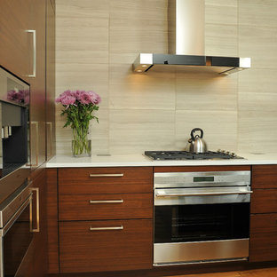 Imagen de cocina en L, actual, de tamaño medio, abierta, con fregadero integrado, armarios con paneles lisos, puertas de armario de madera en tonos medios, encimera de cuarzo compacto, salpicadero beige, una isla, suelo de madera clara, electrodomésticos de acero inoxidable y salpicadero de piedra caliza