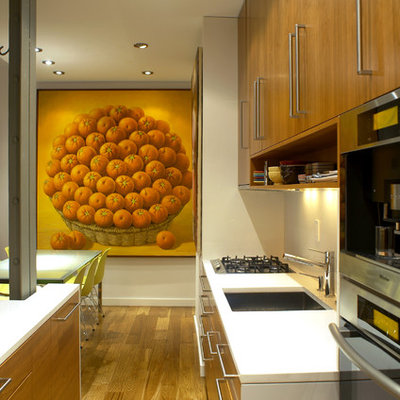 Example of a small minimalist galley medium tone wood floor kitchen design in New York with stainless steel appliances, a single-bowl sink, flat-panel cabinets, medium tone wood cabinets, quartzite countertops and a peninsula