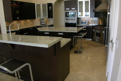 Large contemporary kitchen/diner in Miami with a submerged sink, flat-panel cabinets, dark wood cabinets, granite worktops, grey splashback, stone slab splashback, stainless steel appliances, ceramic flooring and an island.