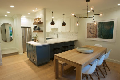 Small minimalist u-shaped light wood floor eat-in kitchen photo in Vancouver with an undermount sink, shaker cabinets, blue cabinets, granite countertops, multicolored backsplash, porcelain backsplash, stainless steel appliances and a peninsula