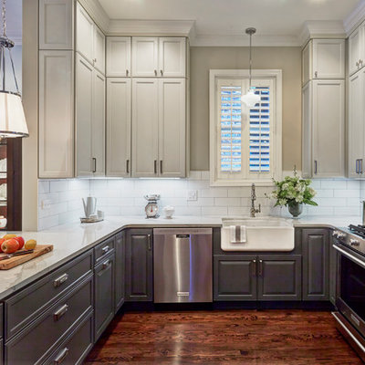Example of a mid-sized farmhouse u-shaped dark wood floor open concept kitchen design in Other with a farmhouse sink, recessed-panel cabinets, gray cabinets, quartz countertops, white backsplash, subway tile backsplash, stainless steel appliances and a peninsula