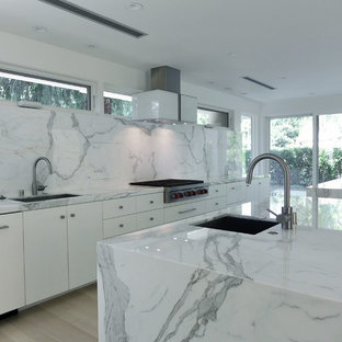 Photo of a large modern single-wall eat-in kitchen in Other with an undermount sink, flat-panel cabinets, white cabinets, marble benchtops, white splashback, stone slab splashback, stainless steel appliances, light hardwood floors and multiple islands.