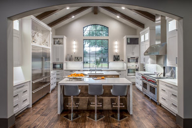 Example of a large minimalist u-shaped medium tone wood floor enclosed kitchen design in Houston with shaker cabinets, white cabinets, quartz countertops, stainless steel appliances and two islands