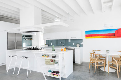 Mid-sized minimalist l-shaped concrete floor and gray floor open concept kitchen photo in Other with an undermount sink, flat-panel cabinets, white cabinets, quartz countertops, gray backsplash, glass sheet backsplash, stainless steel appliances, an island and white countertops