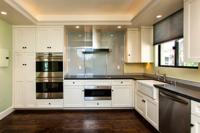Moderne Wohnküche ohne Insel in L-Form mit Landhausspüle, weißen Schränken, Küchengeräten aus Edelstahl und dunklem Holzboden in Santa Barbara