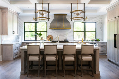 Transitional u-shaped medium tone wood floor, brown floor and coffered ceiling kitchen photo in Minneapolis with an undermount sink, recessed-panel cabinets, light wood cabinets, white backsplash, stone slab backsplash, paneled appliances, an island and white countertops