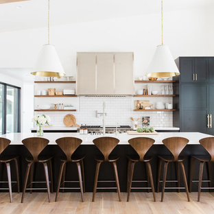 Photo of a transitional kitchen in Salt Lake City with white splashback, subway tile splashback, light hardwood floors, with island, open cabinets and panelled appliances.