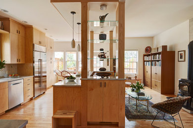 Eat-in kitchen - large modern l-shaped light wood floor and beige floor eat-in kitchen idea in Chicago with a single-bowl sink, flat-panel cabinets, light wood cabinets, glass countertops, gray backsplash, glass tile backsplash, stainless steel appliances and an island