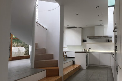 Diseño de cocinas en U actual grande abierto con fregadero encastrado, puertas de armario blancas y electrodomésticos de acero inoxidable
