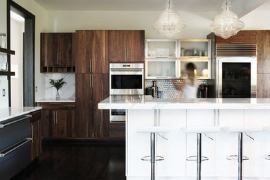 Foto på ett mellanstort funkis vit kök, med en enkel diskho, släta luckor, skåp i mörkt trä, bänkskiva i kvarts, vitt stänkskydd, stänkskydd i metallkakel, rostfria vitvaror, mörkt trägolv, en köksö och brunt golv