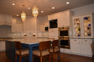 Example of a mid-sized transitional l-shaped medium tone wood floor eat-in kitchen design in Other with shaker cabinets, white cabinets, granite countertops, white backsplash, subway tile backsplash, stainless steel appliances, an island and a farmhouse sink