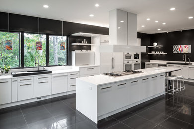 Example of a huge trendy galley porcelain tile open concept kitchen design in Minneapolis with flat-panel cabinets, white cabinets, an island, a single-bowl sink, quartz countertops, white backsplash and white appliances
