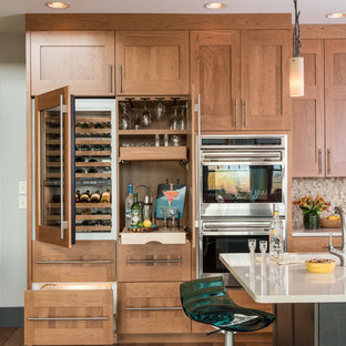 Modelo de cocina clásica renovada, de tamaño medio, con fregadero bajoencimera, armarios estilo shaker, puertas de armario de madera oscura, encimera de cuarzo compacto, salpicadero beige, salpicadero con mosaicos de azulejos, una isla y electrodomésticos de acero inoxidable