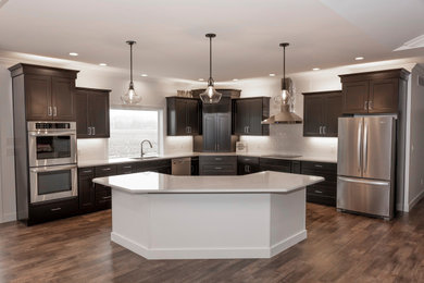 Example of a large transitional l-shaped vinyl floor and brown floor eat-in kitchen design in St Louis with an undermount sink, recessed-panel cabinets, dark wood cabinets, quartz countertops, white backsplash, subway tile backsplash, stainless steel appliances, an island and white countertops