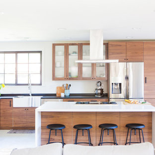 Small midcentury l-shaped open plan kitchen in San Francisco with a farmhouse sink, flat-panel cabinets, medium wood cabinets, multi-coloured splashback, ceramic splashback, stainless steel appliances, porcelain floors, with island, white floor and soapstone benchtops.