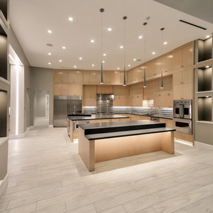 This is an example of a large contemporary l-shaped open plan kitchen in Houston with an integrated sink, flat-panel cabinets, medium wood cabinets, quartz benchtops, multi-coloured splashback, glass tile splashback, stainless steel appliances, porcelain floors and multiple islands.