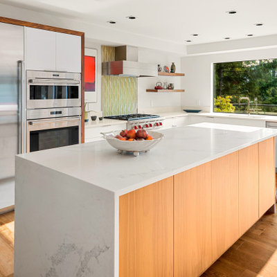 Mid-sized mid-century modern u-shaped light wood floor and beige floor eat-in kitchen photo in Vancouver with an undermount sink, flat-panel cabinets, white cabinets, quartz countertops, green backsplash, glass tile backsplash, stainless steel appliances, an island and white countertops