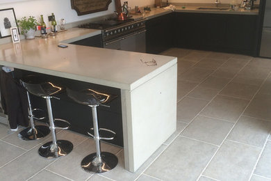 Eat-in kitchen - mid-sized contemporary l-shaped limestone floor eat-in kitchen idea in Gloucestershire with a drop-in sink, flat-panel cabinets, gray cabinets, concrete countertops, white backsplash, stainless steel appliances and a peninsula