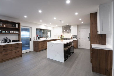Open concept kitchen - contemporary u-shaped porcelain tile and gray floor open concept kitchen idea with an island, a single-bowl sink, flat-panel cabinets, quartz countertops, white countertops, white backsplash and paneled appliances