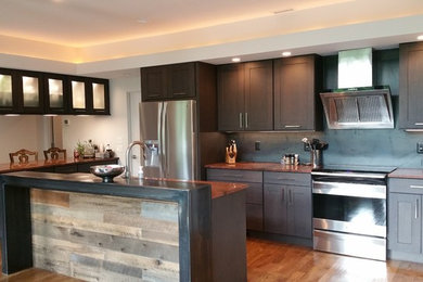 Photo of a large rustic l-shaped kitchen/diner in Other with dark wood cabinets, black splashback, stainless steel appliances, medium hardwood flooring and an island.
