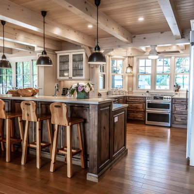 Example of a mid-sized mountain style u-shaped light wood floor and beige floor eat-in kitchen design in Other with an undermount sink, raised-panel cabinets, distressed cabinets, quartz countertops, beige backsplash, wood backsplash, stainless steel appliances, an island and beige countertops