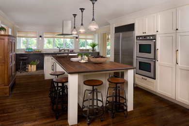 Rustikale Küche mit weißen Schränken, Küchengeräten aus Edelstahl, braunem Holzboden und Kücheninsel in Detroit