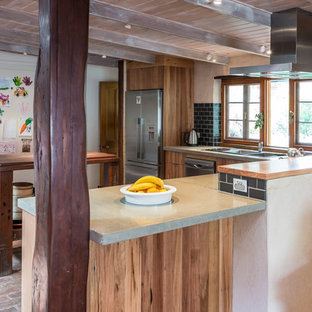 Inspiration for a mid-sized country l-shaped eat-in kitchen in Adelaide with a double-bowl sink, flat-panel cabinets, medium wood cabinets, concrete benchtops, black splashback, subway tile splashback, stainless steel appliances, brick floors and with island.