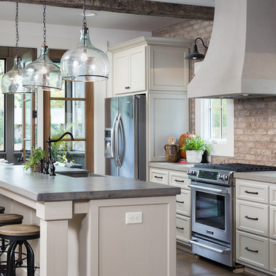 Mid-sized mountain style galley medium tone wood floor open concept kitchen photo in Birmingham with a farmhouse sink, shaker cabinets, white cabinets, concrete countertops, red backsplash, stainless steel appliances and an island