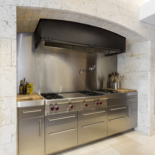 Diseño de cocina comedor lineal, minimalista, grande, con salpicadero metalizado, salpicadero de metal, fregadero bajoencimera, armarios con paneles lisos, puertas de armario de madera oscura, encimera de granito, electrodomésticos de acero inoxidable, suelo de baldosas de porcelana y una isla