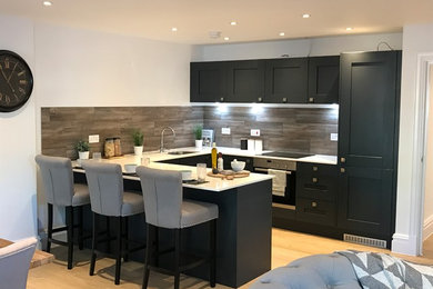 Photo of a medium sized contemporary u-shaped open plan kitchen in Dorset with a built-in sink, shaker cabinets, quartz worktops, multi-coloured splashback, integrated appliances and a breakfast bar.
