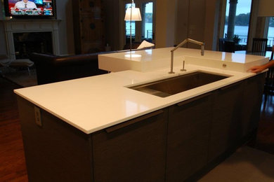 Cette photo montre une cuisine moderne avec un évier encastré, un plan de travail en quartz modifié et îlot.