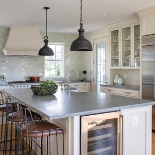Large country eat-in kitchen in DC Metro with a farmhouse sink, concrete benchtops, blue splashback, glass tile splashback, light hardwood floors, with island, grey benchtop, recessed-panel cabinets, beige cabinets, stainless steel appliances and beige floor.