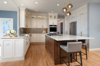 Mid-sized transitional u-shaped light wood floor and brown floor eat-in kitchen photo in Cleveland with an undermount sink, recessed-panel cabinets, white cabinets, granite countertops, gray backsplash, ceramic backsplash, stainless steel appliances, an island and gray countertops