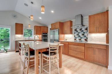Example of a large trendy l-shaped light wood floor and beige floor eat-in kitchen design in Boston with an undermount sink, flat-panel cabinets, light wood cabinets, white backsplash, subway tile backsplash, stainless steel appliances, an island and quartz countertops