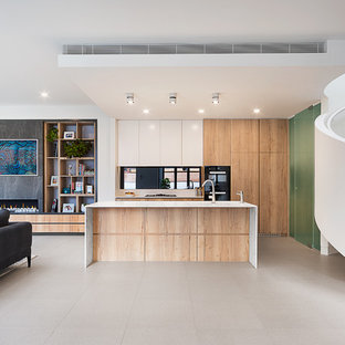 Design ideas for a contemporary l-shaped open plan kitchen in Melbourne with flat-panel cabinets, medium wood cabinets, black appliances, with island, grey floor and white benchtop.