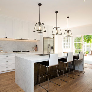 Traditional galley kitchen in Melbourne with a double-bowl sink, shaker cabinets, white cabinets, marble benchtops, marble splashback, stainless steel appliances, medium hardwood floors, brown floor, grey splashback, with island and grey benchtop.
