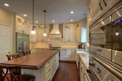Enclosed kitchen - large traditional u-shaped dark wood floor and brown floor enclosed kitchen idea in DC Metro with a farmhouse sink, raised-panel cabinets, white cabinets, granite countertops, white backsplash, ceramic backsplash, stainless steel appliances, an island and beige countertops
