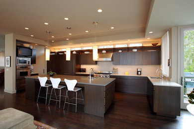Große Moderne Wohnküche in U-Form mit Waschbecken, flächenbündigen Schrankfronten, dunklen Holzschränken, Speckstein-Arbeitsplatte, Küchenrückwand in Weiß, Küchengeräten aus Edelstahl, dunklem Holzboden und Kücheninsel in Seattle