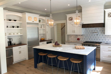 Eat-in kitchen - mid-sized transitional u-shaped medium tone wood floor and brown floor eat-in kitchen idea in Boston with a farmhouse sink, beaded inset cabinets, white cabinets, quartz countertops, stainless steel appliances, an island and gray countertops