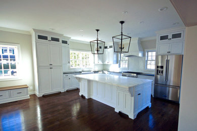Example of a large transitional l-shaped dark wood floor and brown floor open concept kitchen design in Cincinnati with a farmhouse sink, recessed-panel cabinets, white cabinets, marble countertops, white backsplash, subway tile backsplash, stainless steel appliances, an island and white countertops