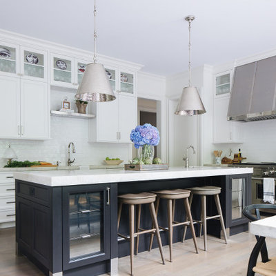 Transitional medium tone wood floor eat-in kitchen photo in Chicago with white cabinets, white backsplash, ceramic backsplash, stainless steel appliances, an island and white countertops