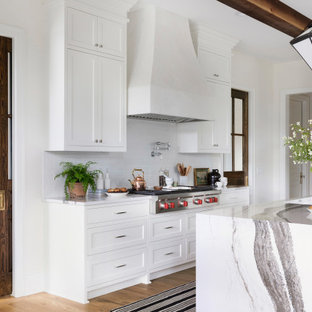 Transitional kitchen remodeling - Inspiration for a transitional medium tone wood floor, brown floor and exposed beam kitchen remodel in Minneapolis with an undermount sink, recessed-panel cabinets, white cabinets, white backsplash, subway tile backsplash, stainless steel appliances, an island and white countertops