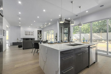 Foto på ett mellanstort funkis vit kök, med en dubbel diskho, släta luckor, bänkskiva i kvarts, rostfria vitvaror, ljust trägolv, en köksö och beiget golv