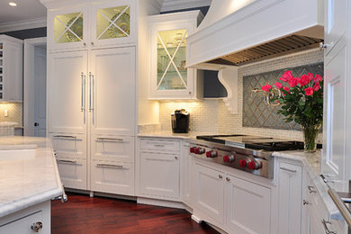 Klassisk inredning av ett kök och matrum, med släta luckor, vita skåp, marmorbänkskiva, flerfärgad stänkskydd, stänkskydd i glaskakel och integrerade vitvaror