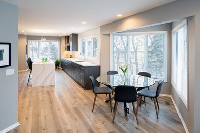 Example of a large minimalist galley light wood floor and brown floor eat-in kitchen design in Grand Rapids with an undermount sink, flat-panel cabinets, dark wood cabinets, quartz countertops, white backsplash, stone tile backsplash, stainless steel appliances, an island and white countertops