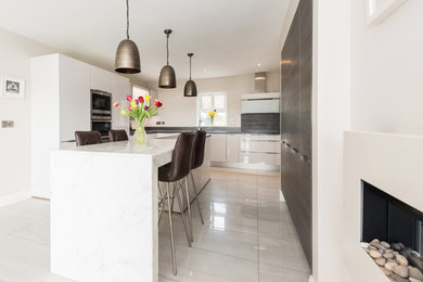 Foto de cocina comedor minimalista con armarios con paneles lisos, puertas de armario blancas, encimera de mármol, electrodomésticos de acero inoxidable, suelo de baldosas de porcelana y una isla