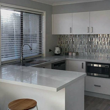 Modern white kitchen with silver metallic recycled glass backsplash