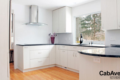 Inredning av ett modernt litet kök, med en enkel diskho, släta luckor, vita skåp, bänkskiva i kvarts, rostfria vitvaror, mellanmörkt trägolv, en halv köksö och brunt golv